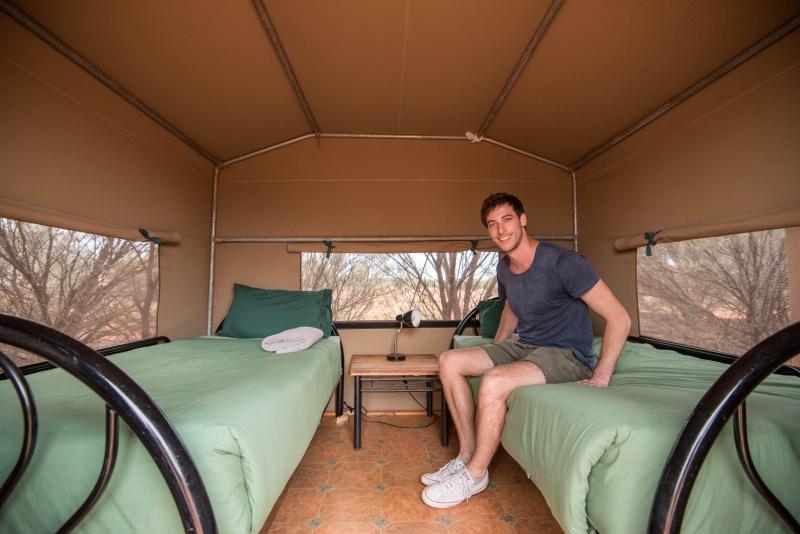 Backpacker sitting in a safari tent on the 2 day 1 night uluru adventure
