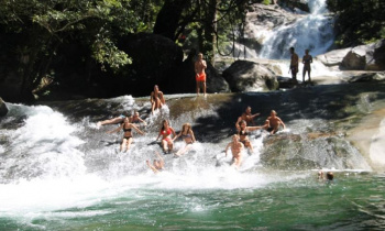 A group of friends sliding down a natural waterslide in the middle of a rainforest
