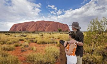 Two people looking at Uluru on a blue sky day on the 3 day Uluru Kata Tjuta & Kings Canyon Tour