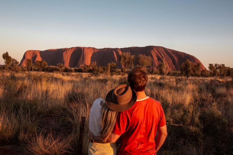 2 backpackers enjoying the view of Uluru during a sunset on the 8 day Uluru to Adelaide experience