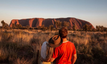2 backpackers enjoying the view of Uluru during a sunset on the 8 day Uluru to Adelaide experience
