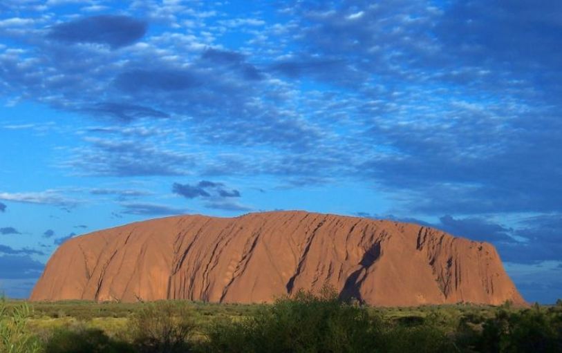 6 backpackers on top of a rock in the Austrlalian outback having fun and jumping in the air on the 3 night Rock the Center tour