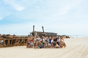A group of friends having fun in front of the Maheno Shipwreck on kgari as part of the discovery noosa day trip