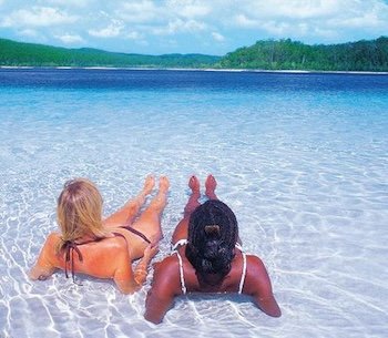 Two female backpackers lounging in the white sands of Lake Mckenzie during a 3 day 2 night Kgari resort stay