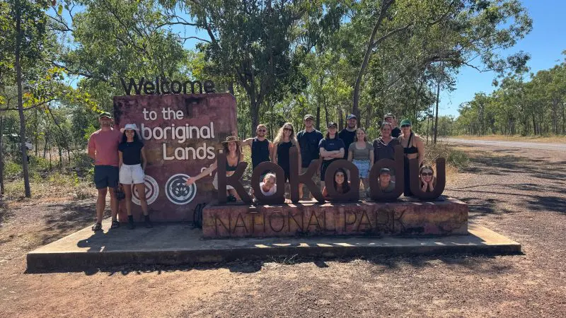 a group of backpakcers at the famous sign at the entrance to Kakadu National Park