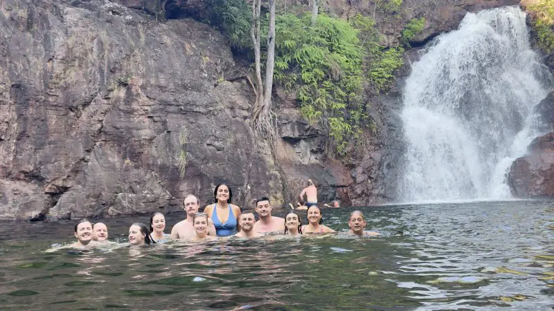 Travellers swim in a clear natural pool near rocky cliffs and a waterfall on a 4 Day Kakadu Katherine Litchfield Adventure tour.