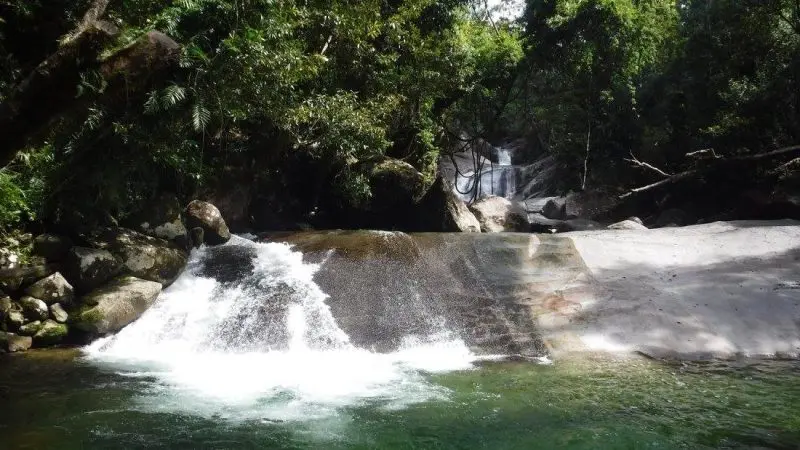 Experience the serene beauty of a cascading waterfall over smooth rocks into a crystal-clear pool on the 1 Day Waterfall Wanderers Tour.