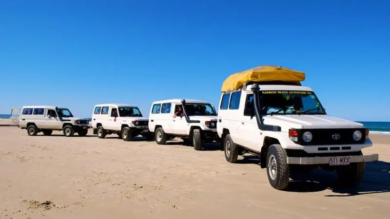 Experience the thrill of four white 4WDs driving along Fraser Island’s pristine sandy beach on a top-rated 2 Day K'gari adventure tour.