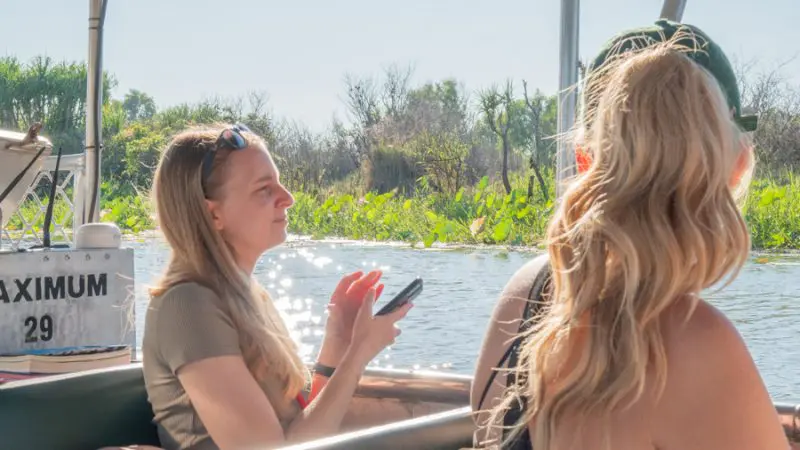 Two women relax on a sunlit boat, taking in scenic views during a 4 Day Kakadu, Katherine, and Litchfield Adventure tour.