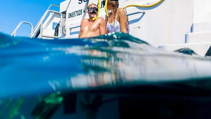 Two snorkellers in swimming costumes and masks relax aboard SCUBAPRO II on a 3-day, 2-night Great Barrier Reef Snorkelling Tour.