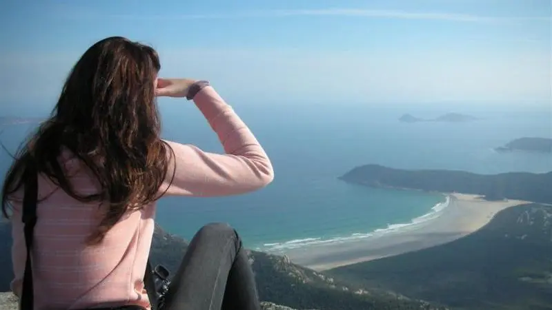 Experience breathtaking views as a woman admires the sea from a cliff on a 1 Day Wilsons Promontory Tour with Go West Tours.