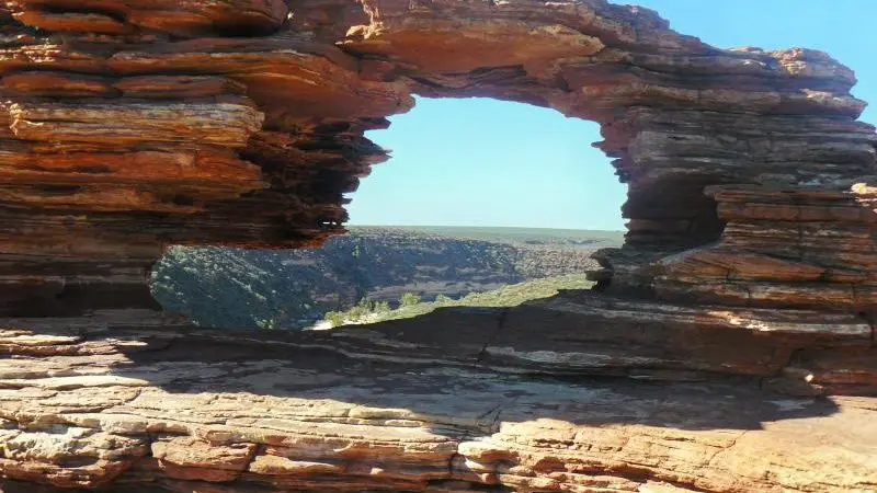 Iconic rock formation featuring a striking natural window, overlooking a scenic valley on the 10 Day Perth to Broome West Coast Adventure.