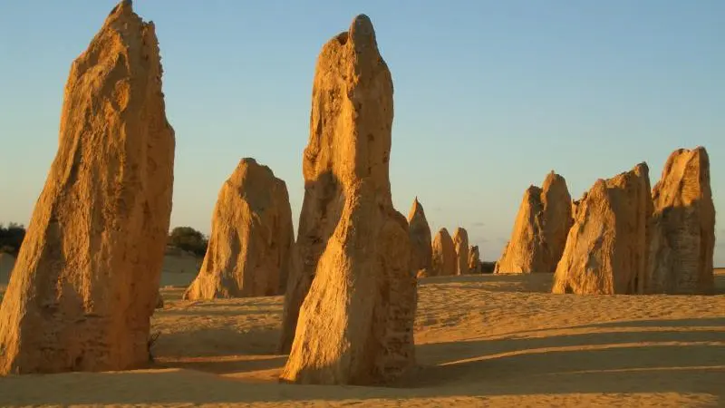 Majestic limestone rock formations illuminated by sunlight line the 10 Day Perth to Broome West Coast Adventure under clear blue skies.