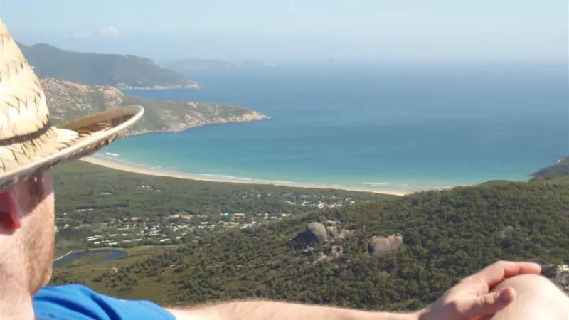 Traveller in a straw hat relaxing and admiring the stunning bay views at Wilsons Promontory during a 1 Day Go West Tours trip.