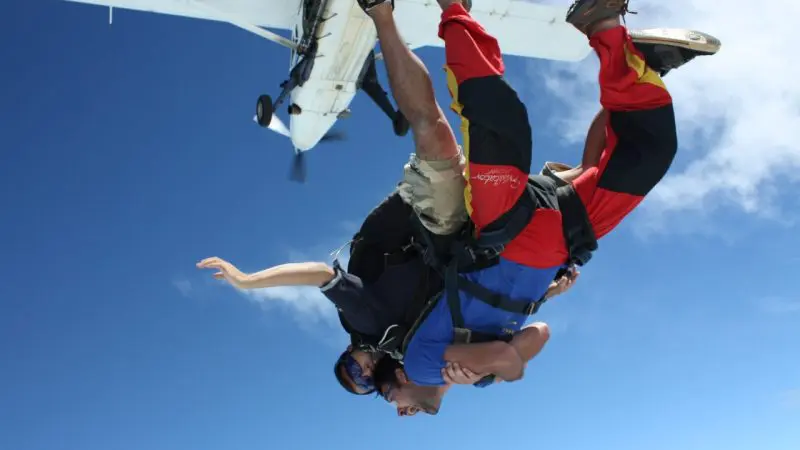 Experience the thrill of tandem skydiving upside down near Sydney with aeroplane overhead, clear blue sky, unforgettable adventure.