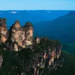 The iconic Three Sisters sandstone peaks tower over lush forest in Australia’s Blue Mountains, a must-see on 1 Day Blue Mountains Tours.