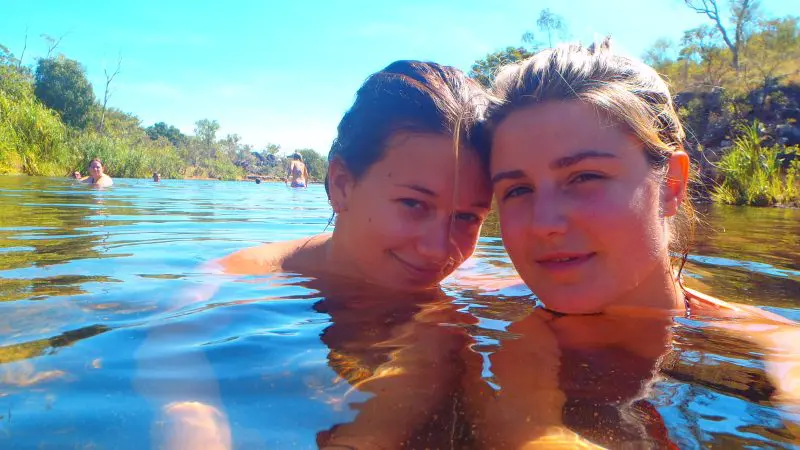 Two young women take a joyful selfie in a crystal-clear natural pool during a 3-Day Kakadu Adventure Camping trip, June–September.