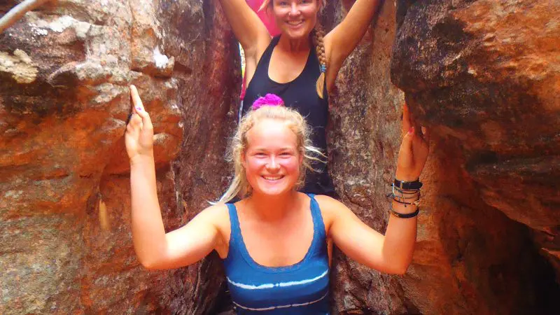 Three happy women posing in a sunlit Kakadu canyon on a 3 Day Adventure Camping tour, June–September; unforgettable outback experience.