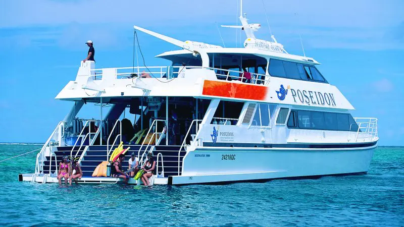 Adventure seekers gear up for a Poseidon Snorkel Dive from a pristine white boat anchored in crystal-clear blue tropical waters.