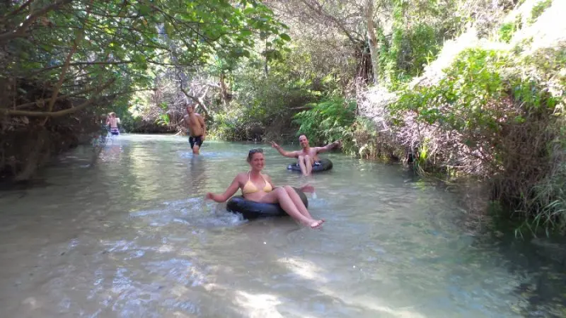 Experience two adventurers relaxing on rubber rings in a crystal-clear stream, surrounded by lush nature on a Kgari 2 Day Tour from Hervey Bay.