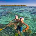 Snorkellers explore crystal-clear waters near lush Green Island on a popular Half-Day Tour, 1pm departure, top-rated tropical adventure.