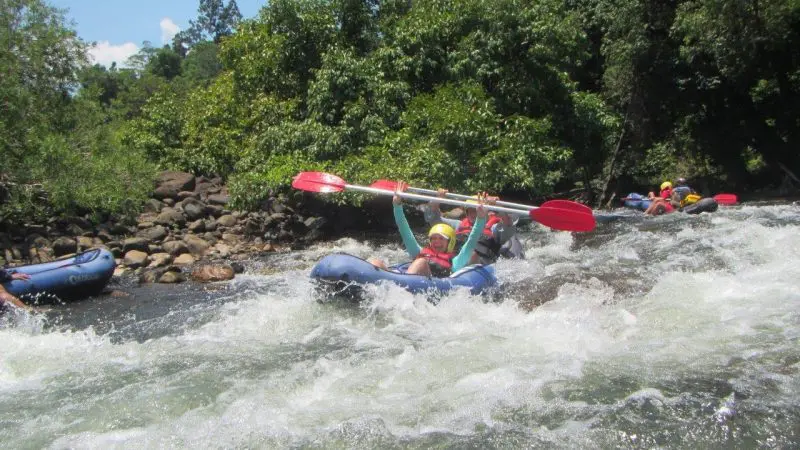 Adventurers wearing helmets and life jackets navigate thrilling white-water rapids on a full-day sports rafting tour near Mission Beach.