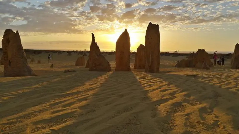 Majestic limestone pillars cast dramatic sunset shadows across golden desert sands on the 8-Day Perth to Exmouth Return Tour.
