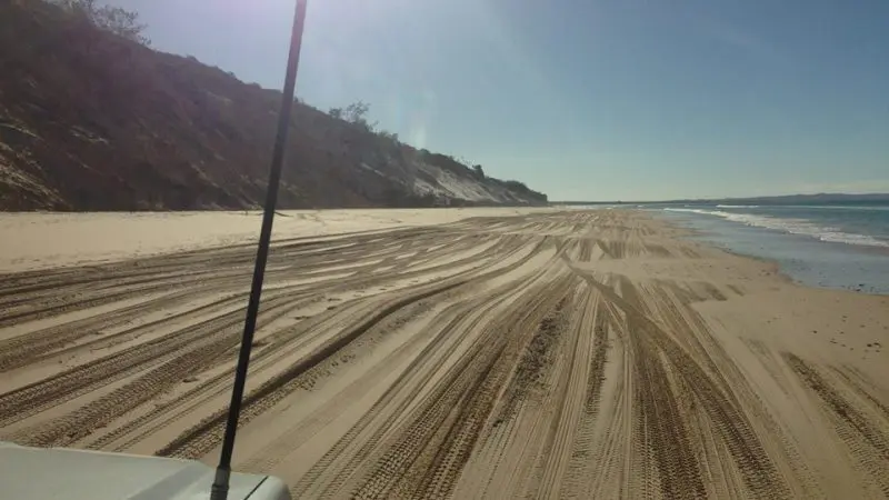Experience Australia’s longest surfable wave from a vehicle on Beach Drive, with sandy shores, tyre tracks, and scenic dunes.