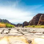 Traveller trekking across a rugged, sunlit riverbed on the 10 Day Broome to Darwin Kimberley Off Road Adventure Tours experience.