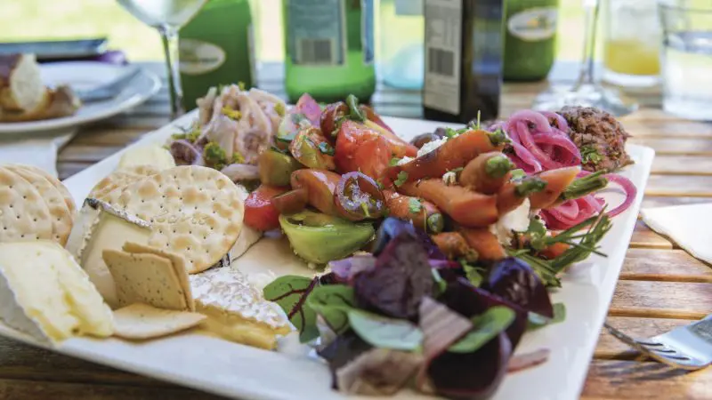 Indulge in a gourmet plate of artisan cheeses, premium crackers, and fresh salad on the McLaren Vale North Hop On Hop Off Tour.