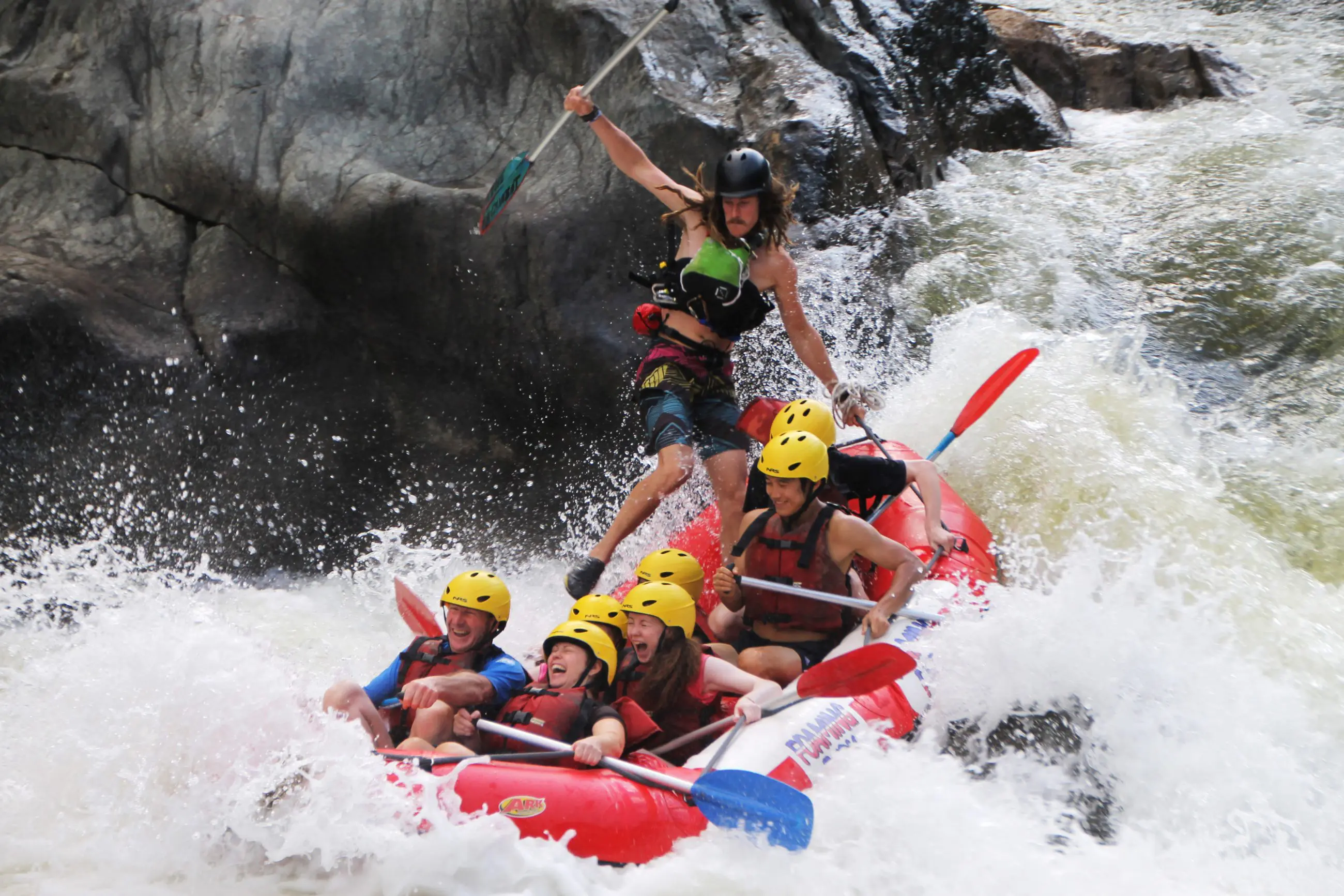 Adventure seekers in helmets and life jackets navigate thrilling Barron River rapids on a half-day white-water rafting near Cairns.