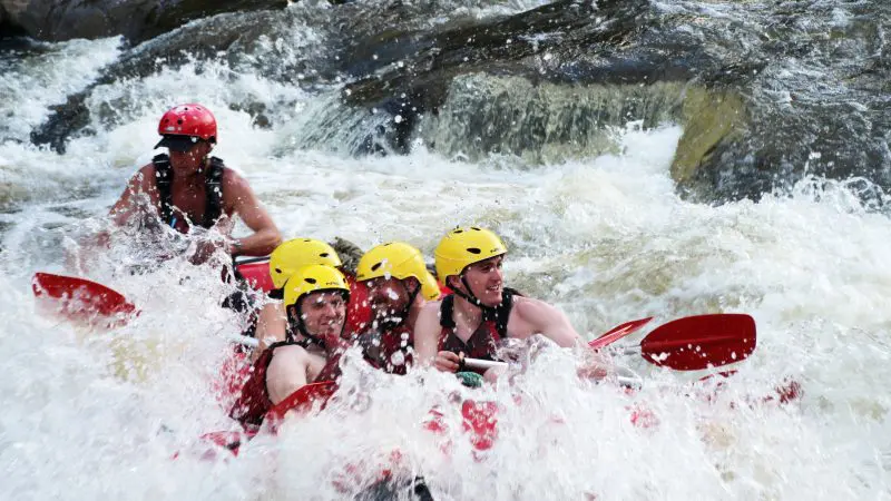 Adventurers in helmets and vests raft through powerful Barron River rapids on a top-rated Port Douglas white water rafting tour.