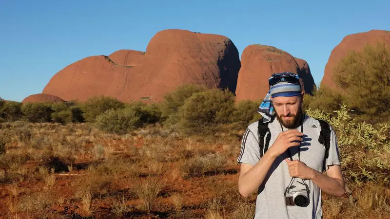 A traveller with a camera explores the desert landscape on the 3 Night Rock The Centre Yulara To Yulara adventure tour in Australia.