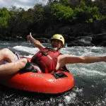 Smiling man wearing a yellow helmet and red vest gives thumbs up during Foaming Fury half-day river tubing adventure experience.