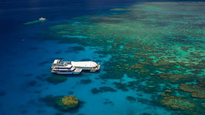 A spacious boat is anchored by the lively Great Barrier Reef Activity Platform, surrounded by crystal-clear blue ocean waters.