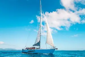 Picture of travellers Experiencing the ultimate Whitsunday adventure as a group glides a white sailboat with Hammer 2 Day 2 Night Sailing on calm blue seas.