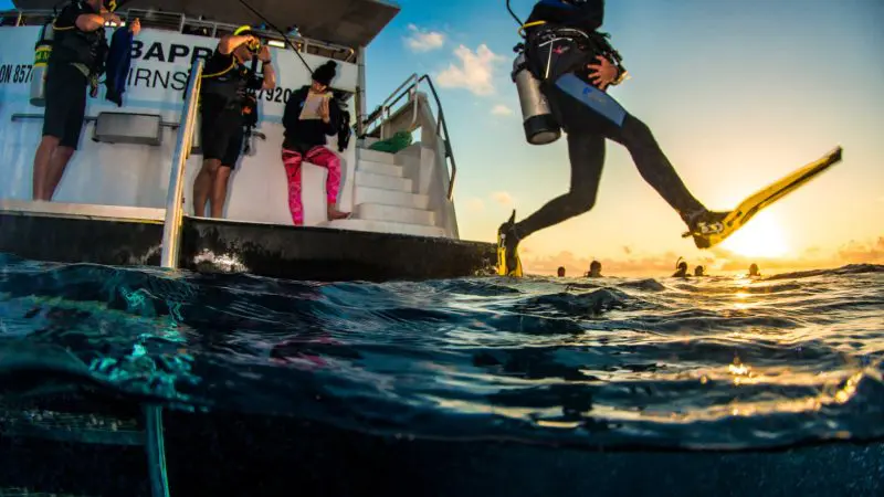 Scuba diver enters the ocean at sunset on a 4-Day Learn to Dive Elearning Liveaboard—ultimate training and adventure experience.