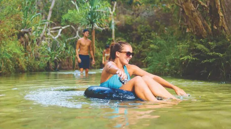 Adventurous woman in blue swimming costume tubing on crystal-clear creek during 2 Day K'gari Fraser Island Tag Along Adventure with Dingos tour.