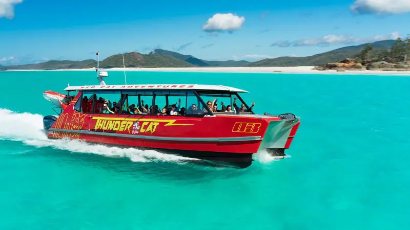 Experience the Thundercat 1 Day Whitsunday Islands Adventure gliding on turquoise waters by pristine white sands and lush green hills.