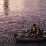 Two kayakers with bright yellow paddles float on calm waters at sunset—Friday or Saturday night tours only, no catering included.