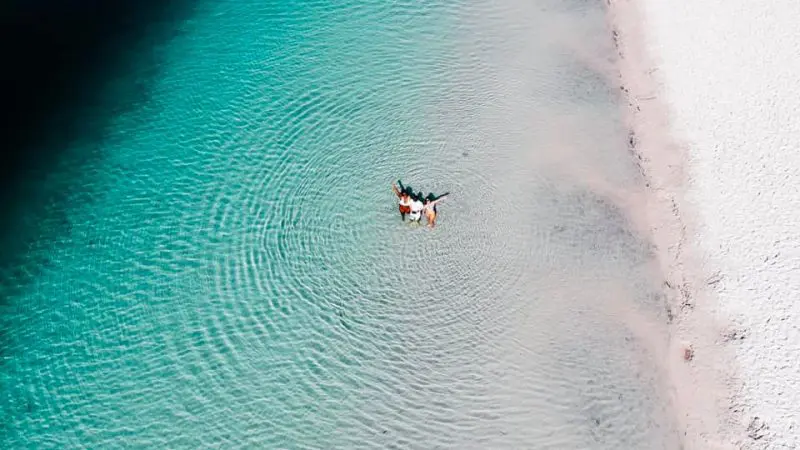 Experience two people floating in crystal-clear turquoise waters by a pristine sandy beach on a 3 Day K'gari Tour from Rainbow Beach.