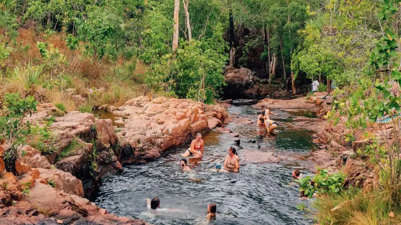 Visitors swimming and unwinding in a scenic rocky stream during a 1 Day Litchfield National Park Crocodile Cruise adventure tour.
