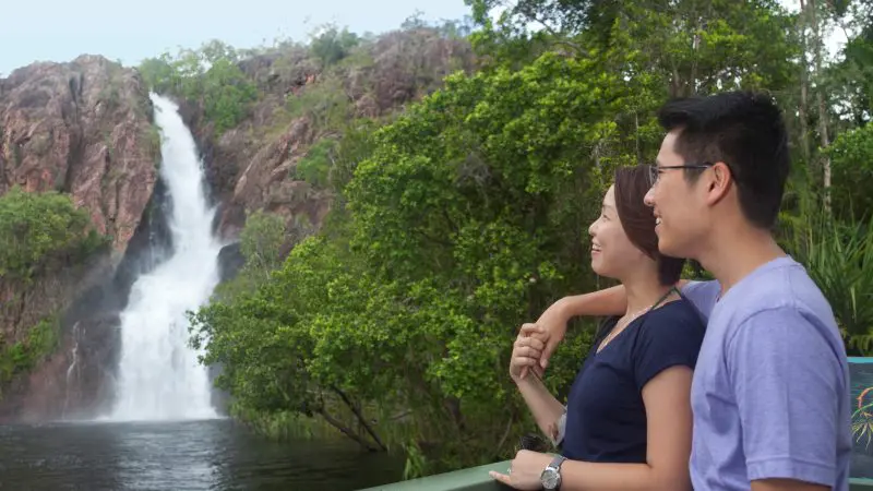 Happy couple by a railing marvel at a stunning waterfall during a 1 Day Litchfield National Park Crocodile Cruise adventure tour.