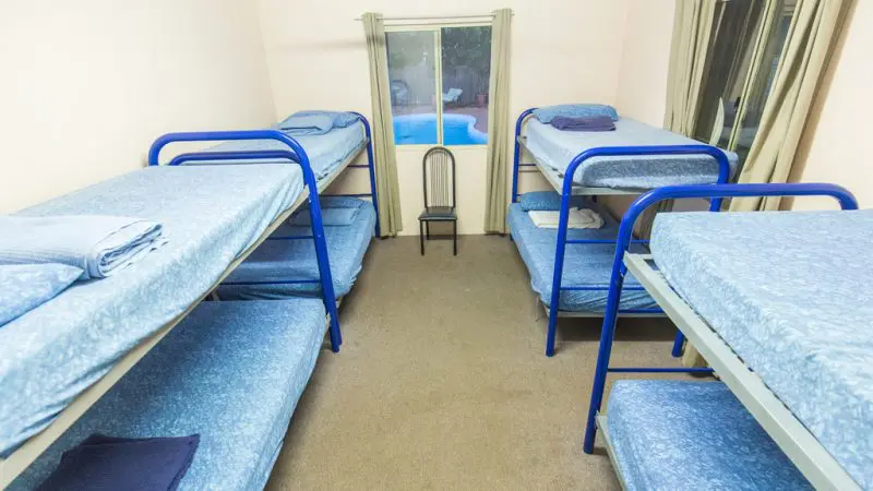 Compact room featuring six blue bunk beds, ideal group accommodation for Perth to Darwin tours excluding Broome stay.