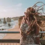 Woman with windswept hair enjoys panoramic cliff views along the Great Ocean Road during a 1 Day Reverse Eco Tour adventure.