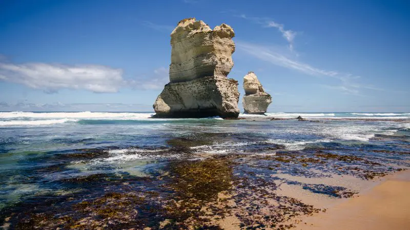 Majestic limestone rock formations along the Great Ocean Road, captured on a 1 Day Reverse Eco Tour beneath a vibrant blue sky.
