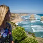 Blonde woman gazes at dramatic ocean cliffs during the 3 Day Great Ocean Road Melbourne to Adelaide Explorer tour, scenic coastline views.