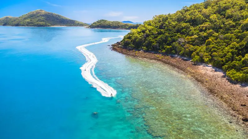 A speedboat creates a foamy white wake near vibrant green islands during the Two Island Safari 2 Hour Jetski Tour adventure.