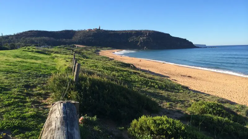 Experience a stunning sunny beach with golden sand, lush green grass, and scenic hills—perfect for Celebtime Tours’ 1 Day getaway.