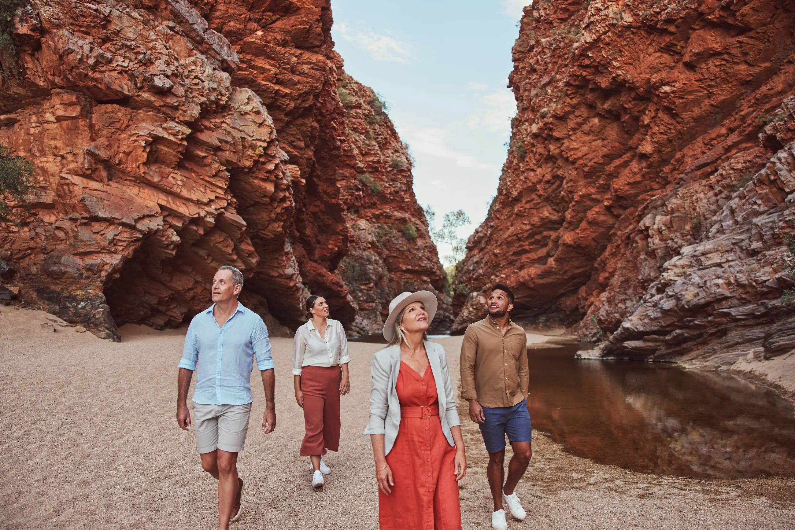 Four adventurers marvel at dramatic red cliffs and a crystal-clear pool on a 1 Day West MacDonnell Ranges tour with Standley Chasm.